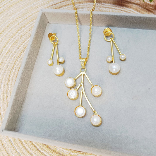 Close-up of gold tone pearl pendant set on grey tray – handcrafted minimalist jewelry by Gemsara.