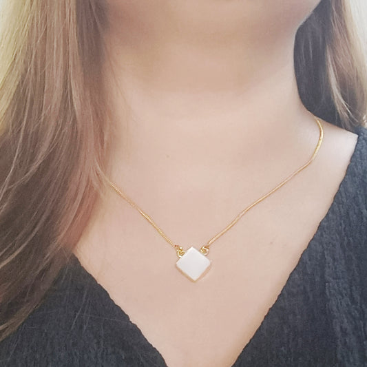 Model wearing Mother of Pearl necklace in gold tone – dainty square pendant with soft iridescent glow.
