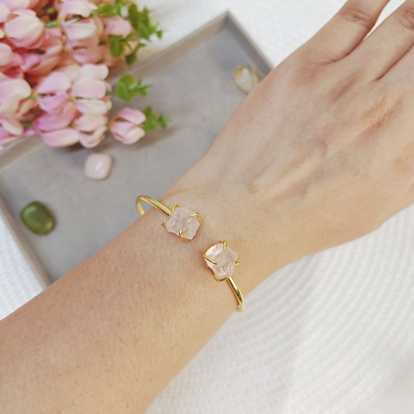 Hand wearing a baby pink stone adjustable bangle, hand wearing a rose quartz cuff bangle